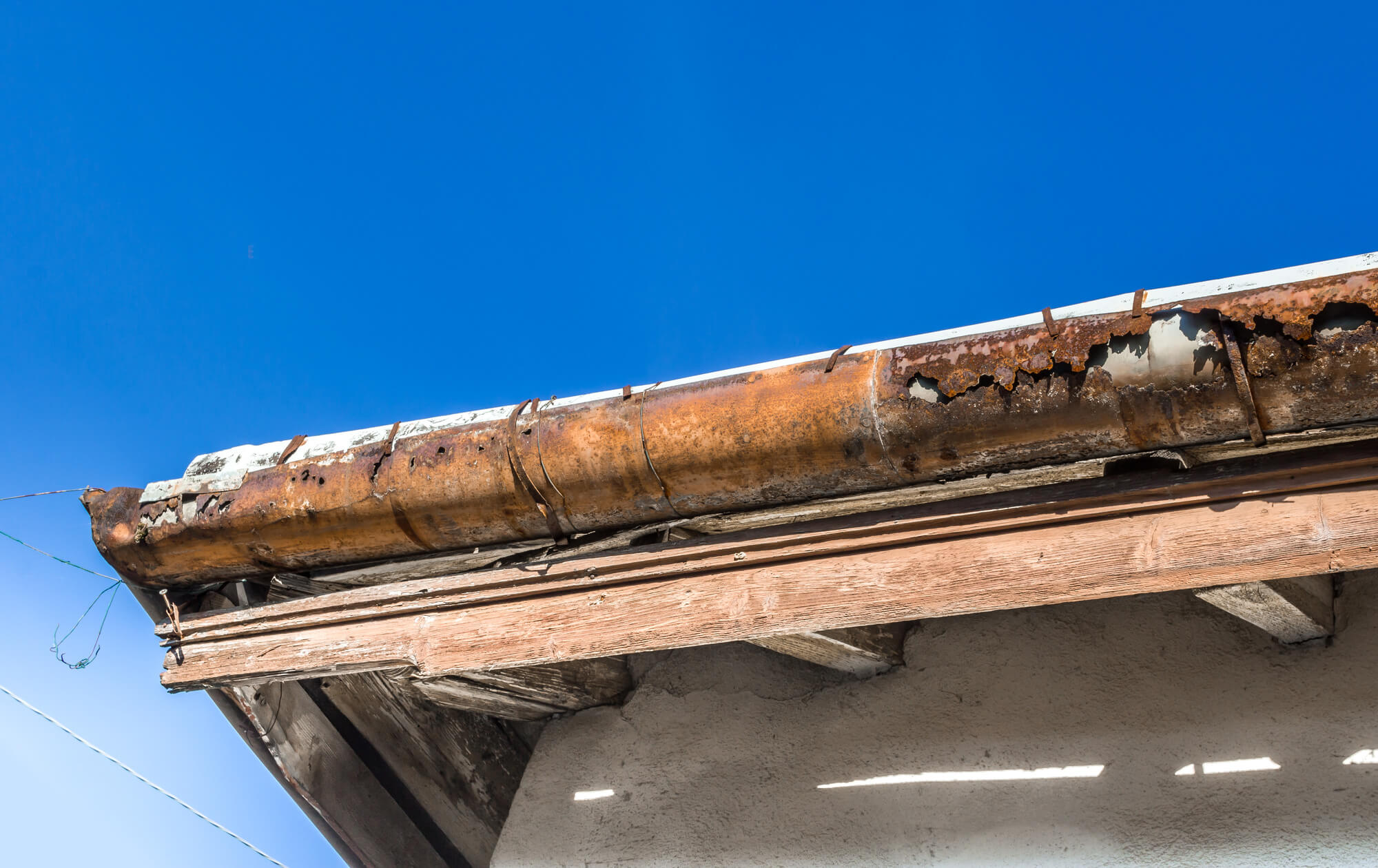 Rain gutters on an old home with a blue sky in the background.